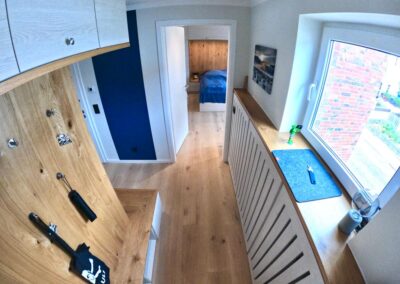 Blick in den Flur Richtung Schlafzimmer, Fenster mit Blick nach Norden, Holzfußboden und Holzverkleidung, Schränke und Sitzgelegenheit