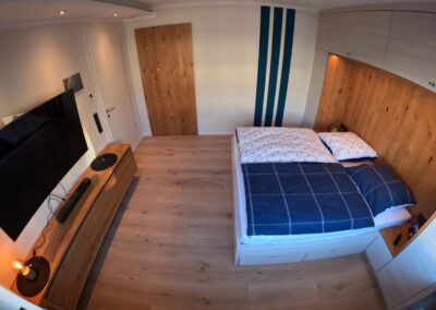 Schlafzimmer mit großem Bett, Fernseher, gemütlichem Blick, Leselicht, Musiksystem, Holzfußboden,